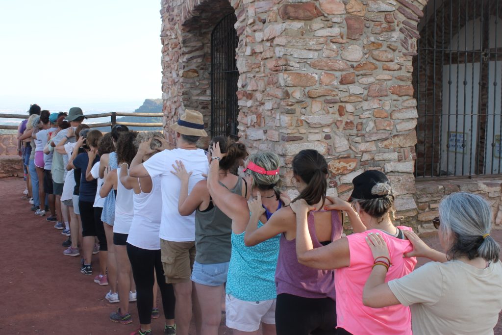 Grupo de participantes realizando una dinámica de conexión y confianza durante un retiro de verano en la Sierra de Mariola, Alicante.