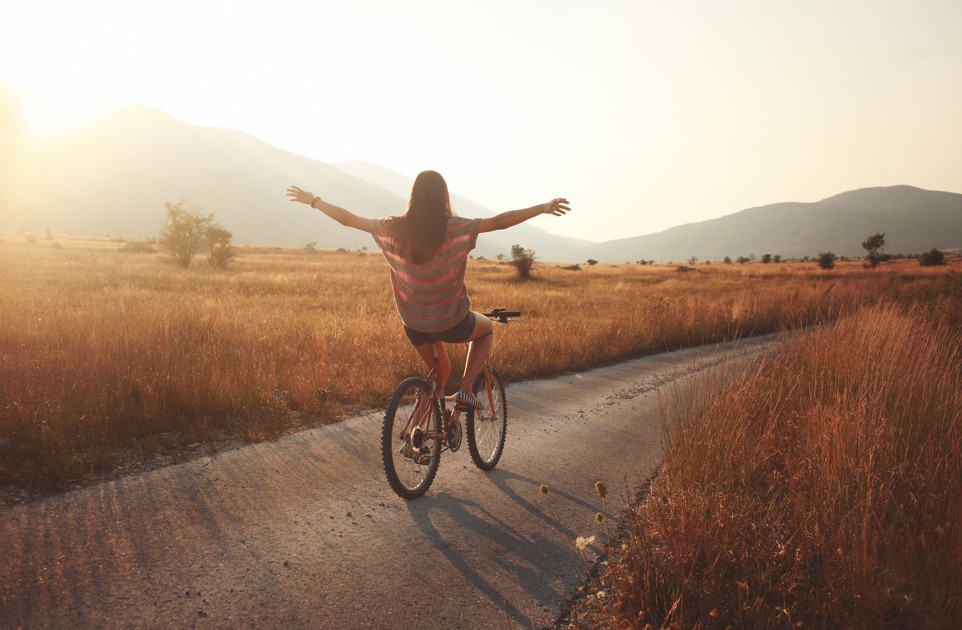 Mujer en bicicleta recorriendo un camino y experimentando libertad